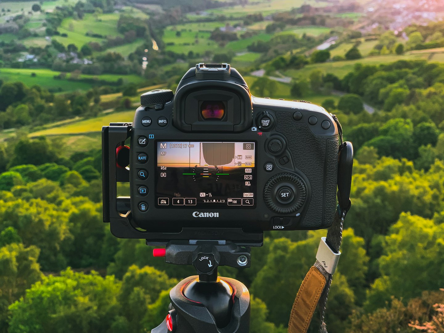 DSLR-Kamera auf einem Stativ blickt auf eine grüne Talschaft.