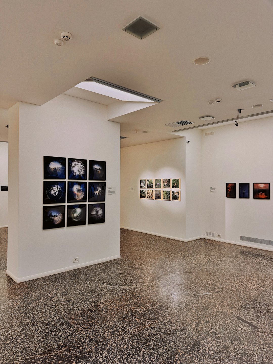 Leerer moderner Kunstgalerie-Saal mit gerahmten Bildern an weißen Wänden.
