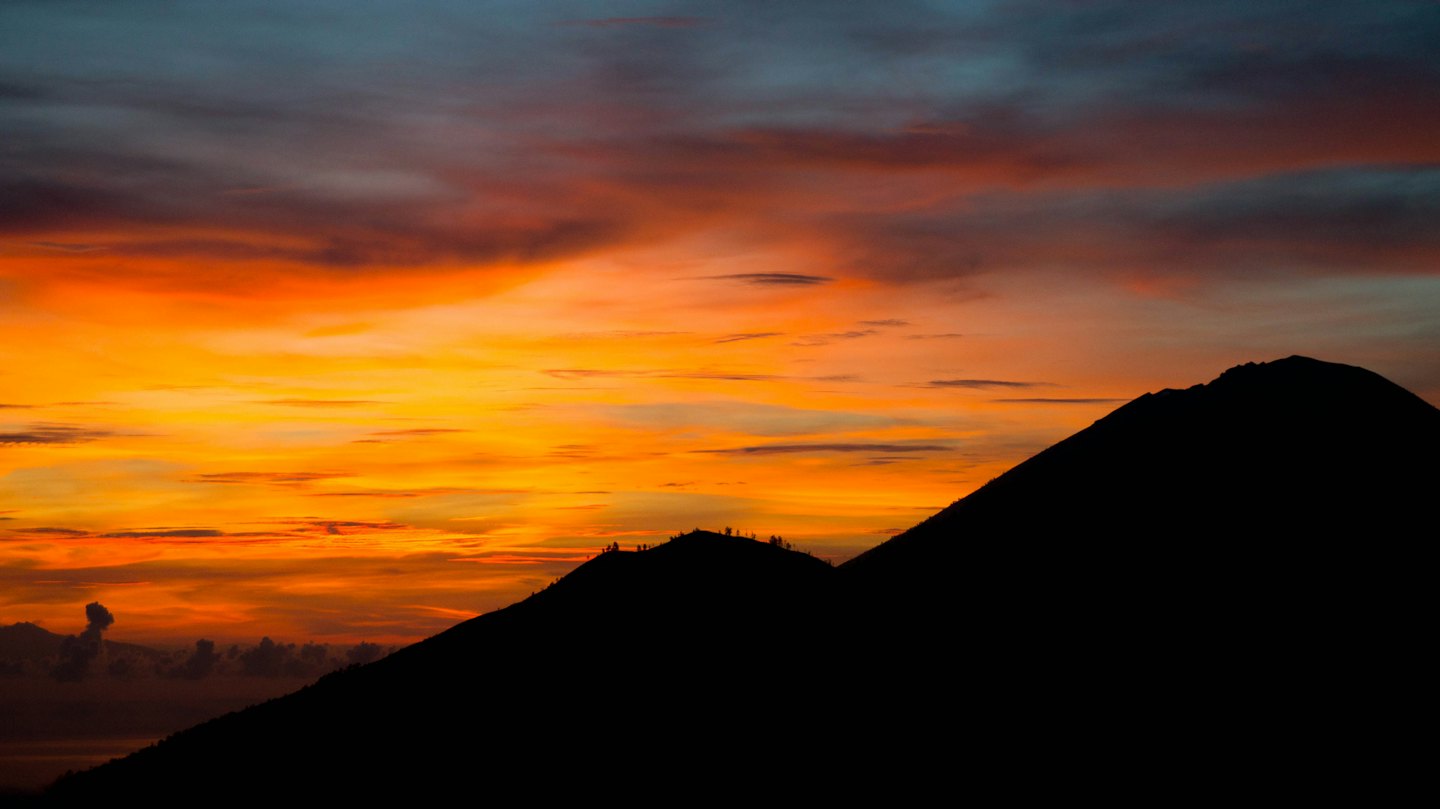 Gebirgskette vor einem farbenfrohen Sonnenuntergangshimmel.